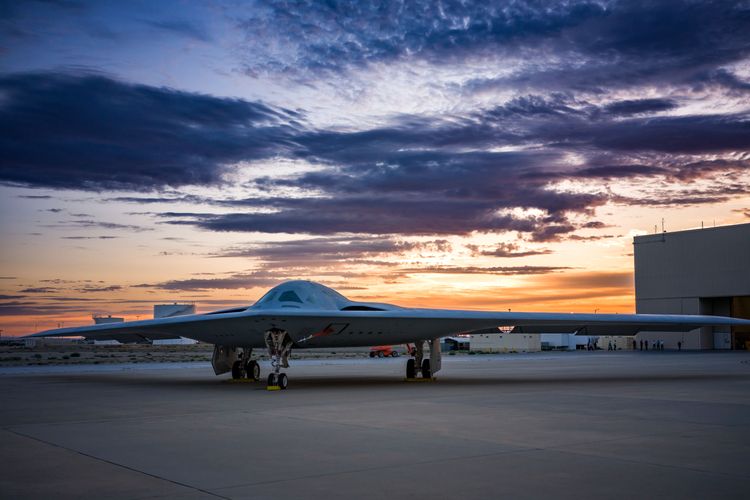 A B-21 sits on the ground under a sunset. The Air Force awarded a contract for its development to Northrop Grumman in 2015. Now, seven years later, it is ready for flight testing.