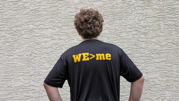 A Westerville North High School athlete displays his team shirt with the words WE>me. A method of building strong culture through a reminder to work together with every other teammate. 