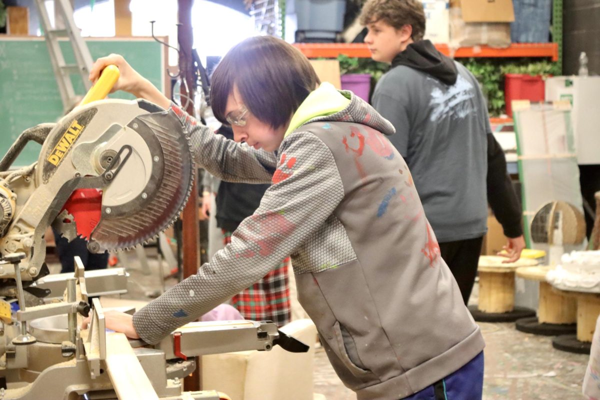Wood Saw: Tech crew member works on set by cutting wood for frames 