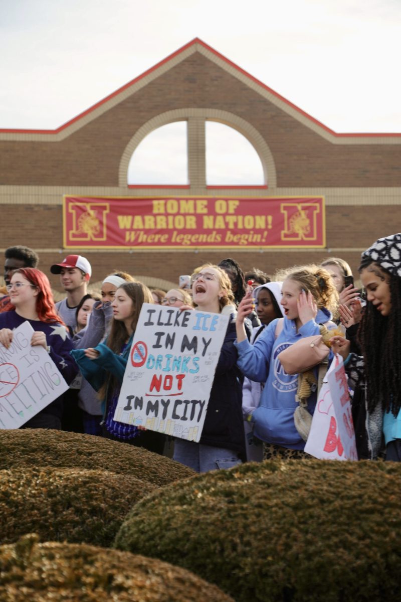 Students are gathered around the flagpole cheering on and listening to the various speakers during the protest. 
